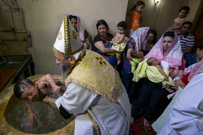 Priest baptizes a child at Coptic Orthodox Church of Virigin Mary in Cairo suburb